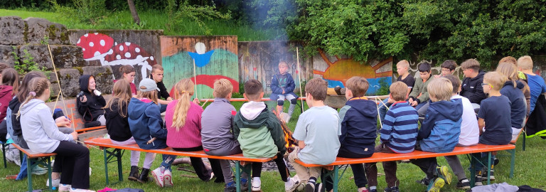 Kinder sitzen ums Lagerfeuer