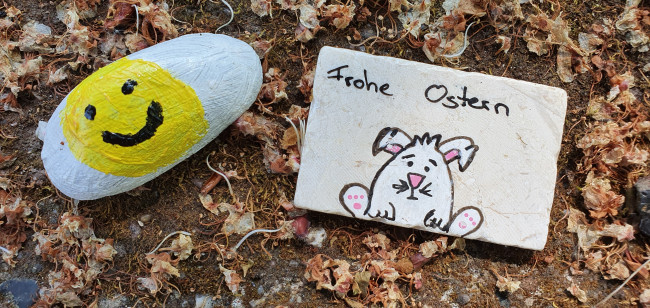 Ein Stein mit Smiley und ein Text Frohe Ostern